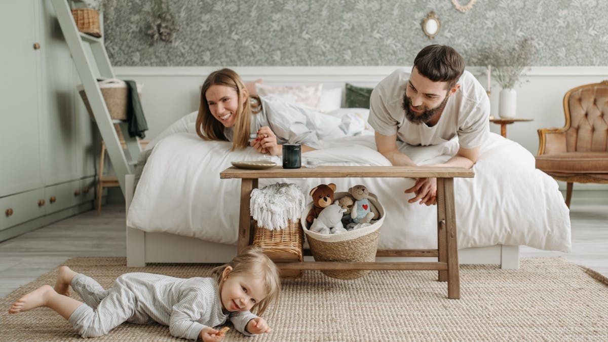 A joyful family bonding in a cozy bedroom, featuring a playful child and loving parents.
