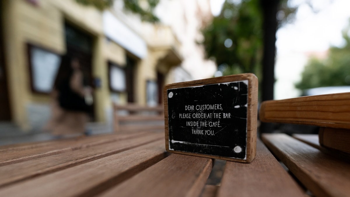 A close up of a wooden bench with a sign on it